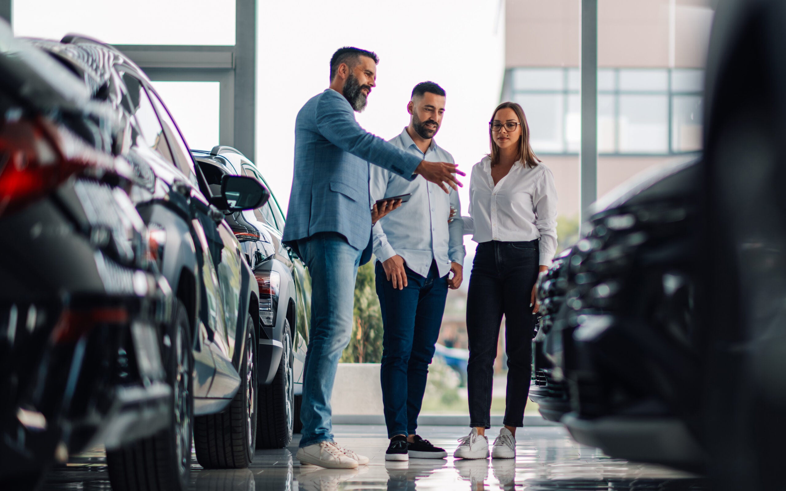 Automotive salesman speaking to customers in showroom
