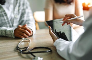 Patient and spouse listening to doctor at desk